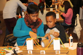 adult and child working together on a model of a bridge