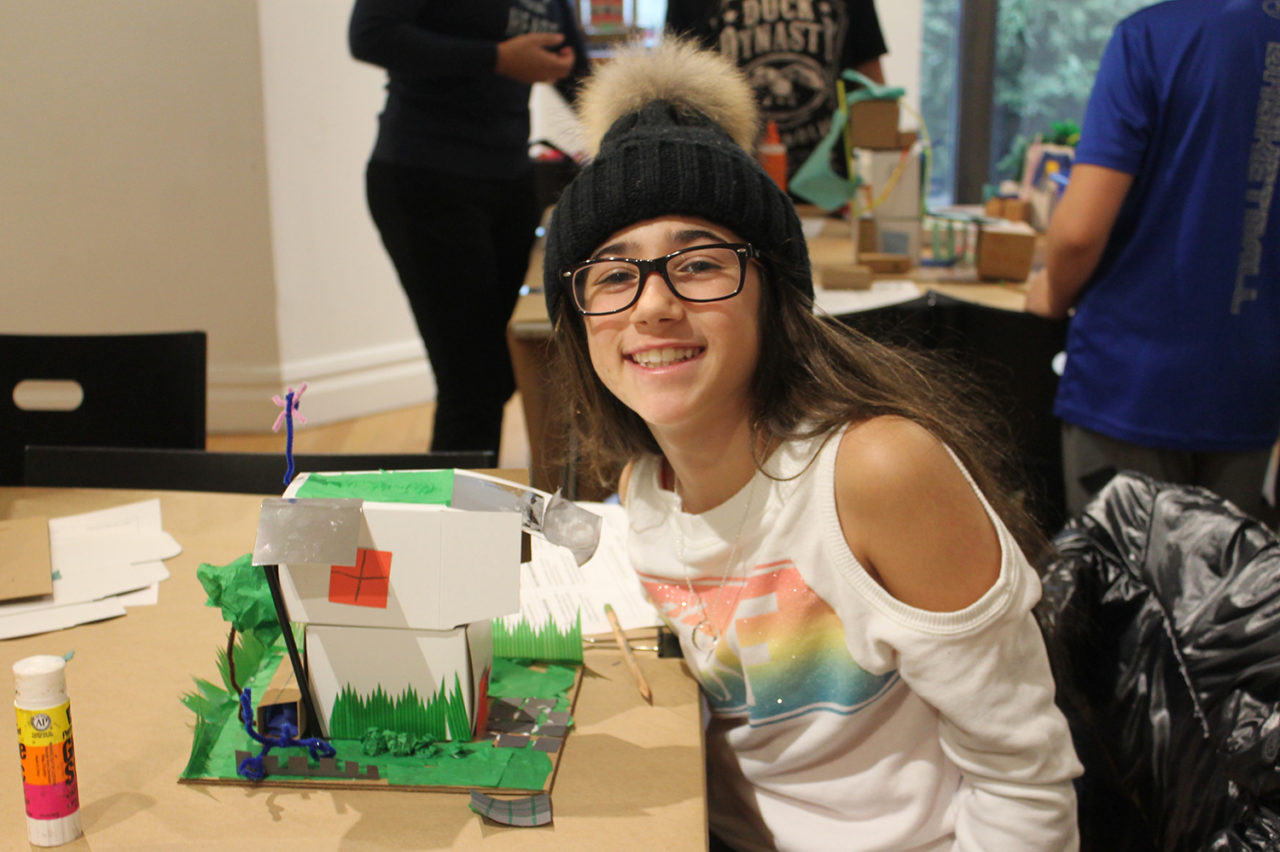 A student poses with her finished model, highlighting the importance of adding greenery and using renewable energy sources. Credit: Center for Architecture.
