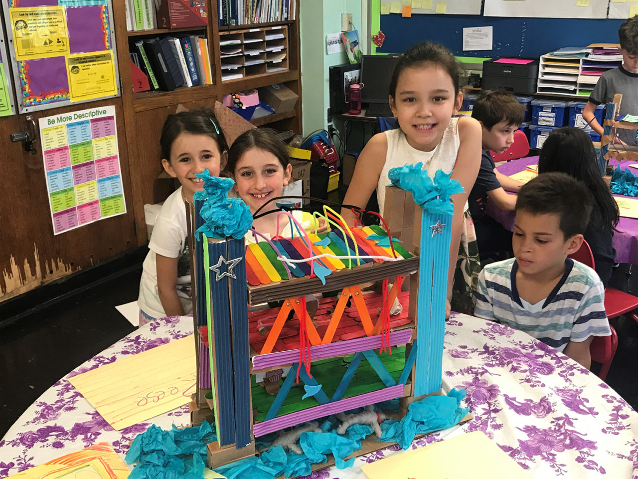 PS 33M: Second grade students proudly display the truss bridge they designed and built with  Design Educator Mary Lib Schmidt. Students learned about four different types of bridges over the course of this eight-session program, then created their own bridge designs.