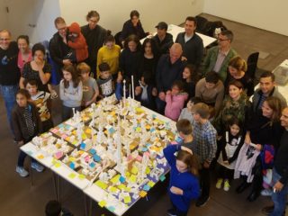 Families standing around a model city built of legos