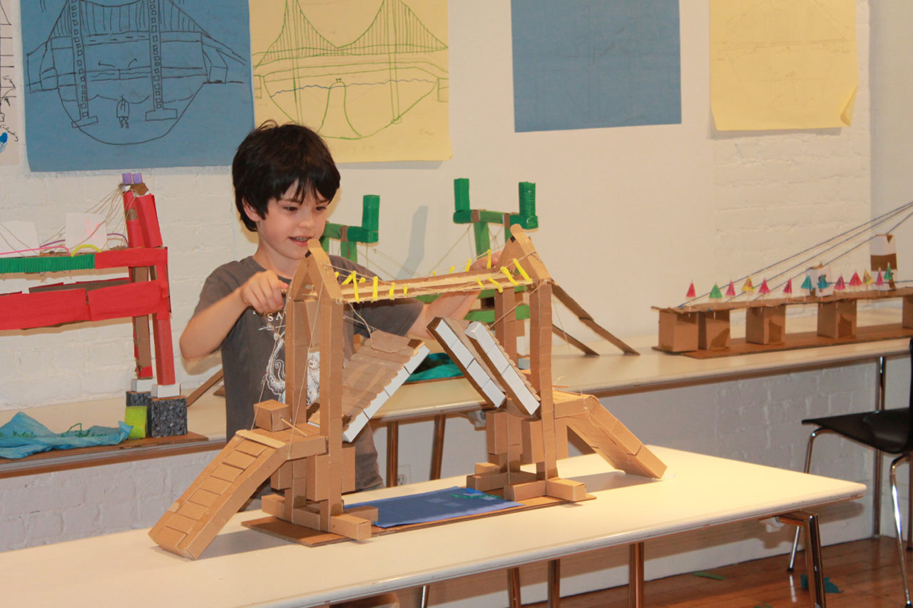 An elementary school student proudly demonstrates his moving bridge to friends and family during final presentations. Image credit: Center for Architecture.