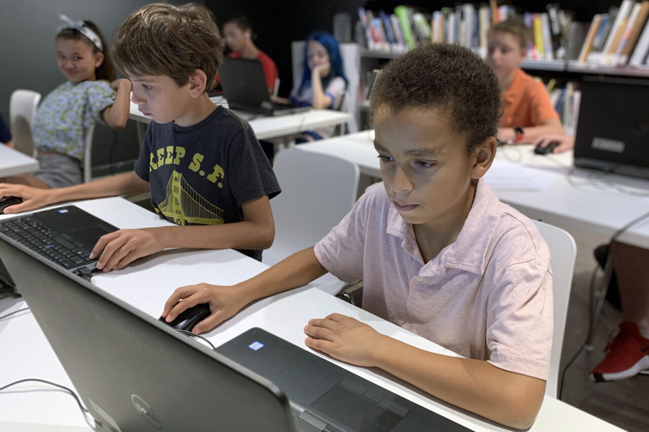 Two middle school student sitting behind their laptops working on digital models.