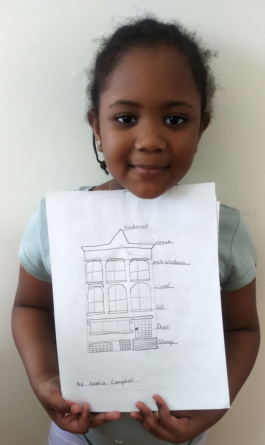A young student shows off her rowhouse drawing. Photo: Trudie Stoddar Barrett.