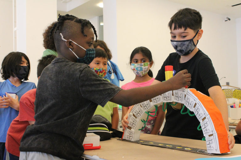 Photo of two students testing the strength of bridges they constructed during one of the Center for Architecture's Summer Programs.