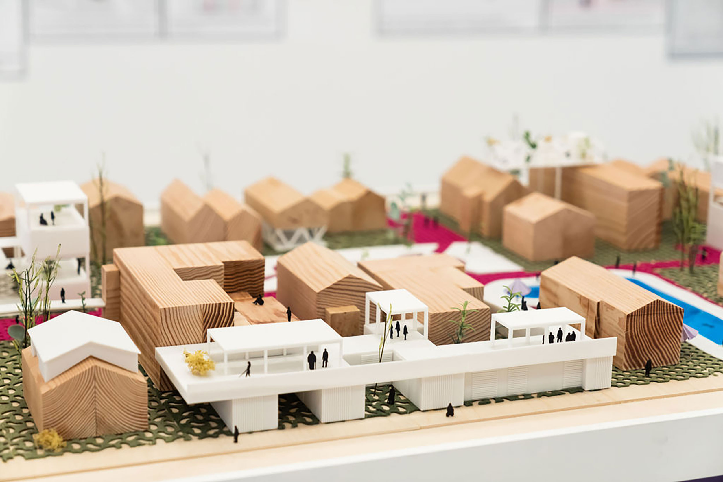 Three-dimensional model of a site with several buildings, some made of wood and others 3D printed in white plastic.