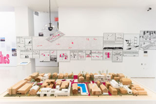 Three-dimensional model of a site with several buildings, some made of wood and others 3D printed in white plastic.