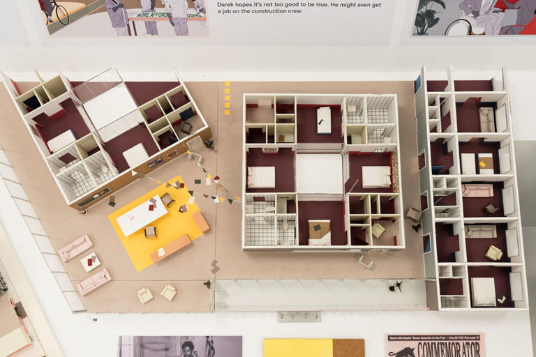 Three-dimensional model of the interior of one floor of a residential building, featuring several dormitory spaces with private bathrooms as well as a large communal area with tables, couches, and a terrace.