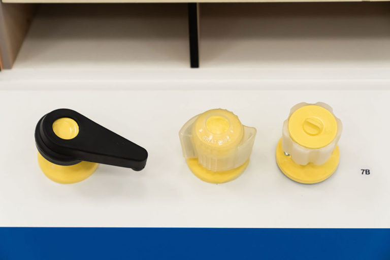 Three round, yellow doorknobs, each featuring a different style of rubber grip.