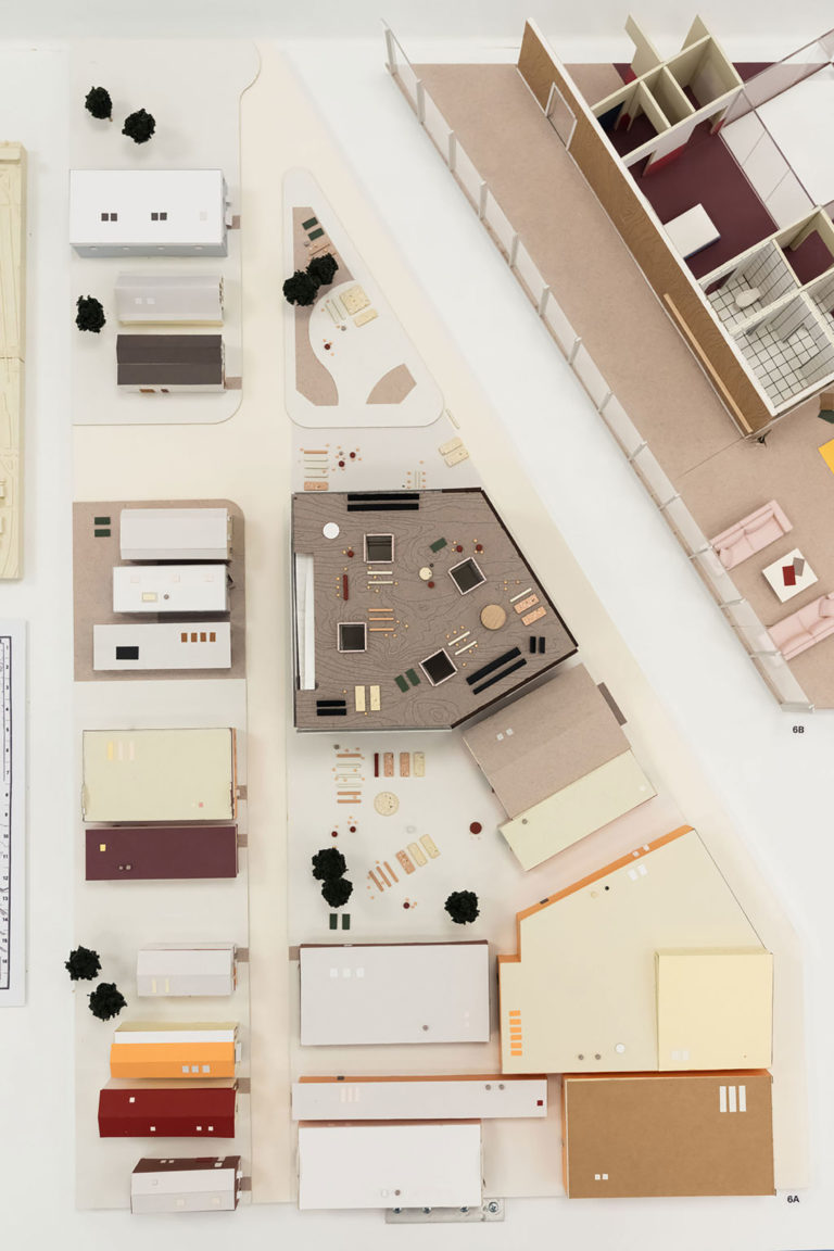 Three-dimensional model of an irregularly shaped lot with 20 buildings of different sizes and two open spaces arranged throughout the site.