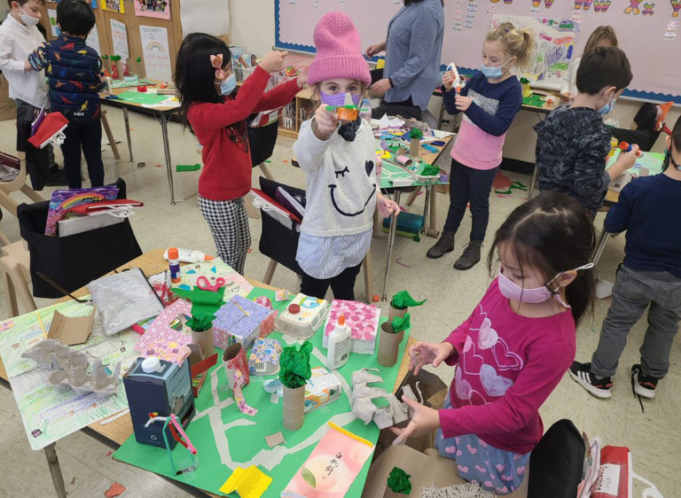 Grade school students in a classroom build architectural models