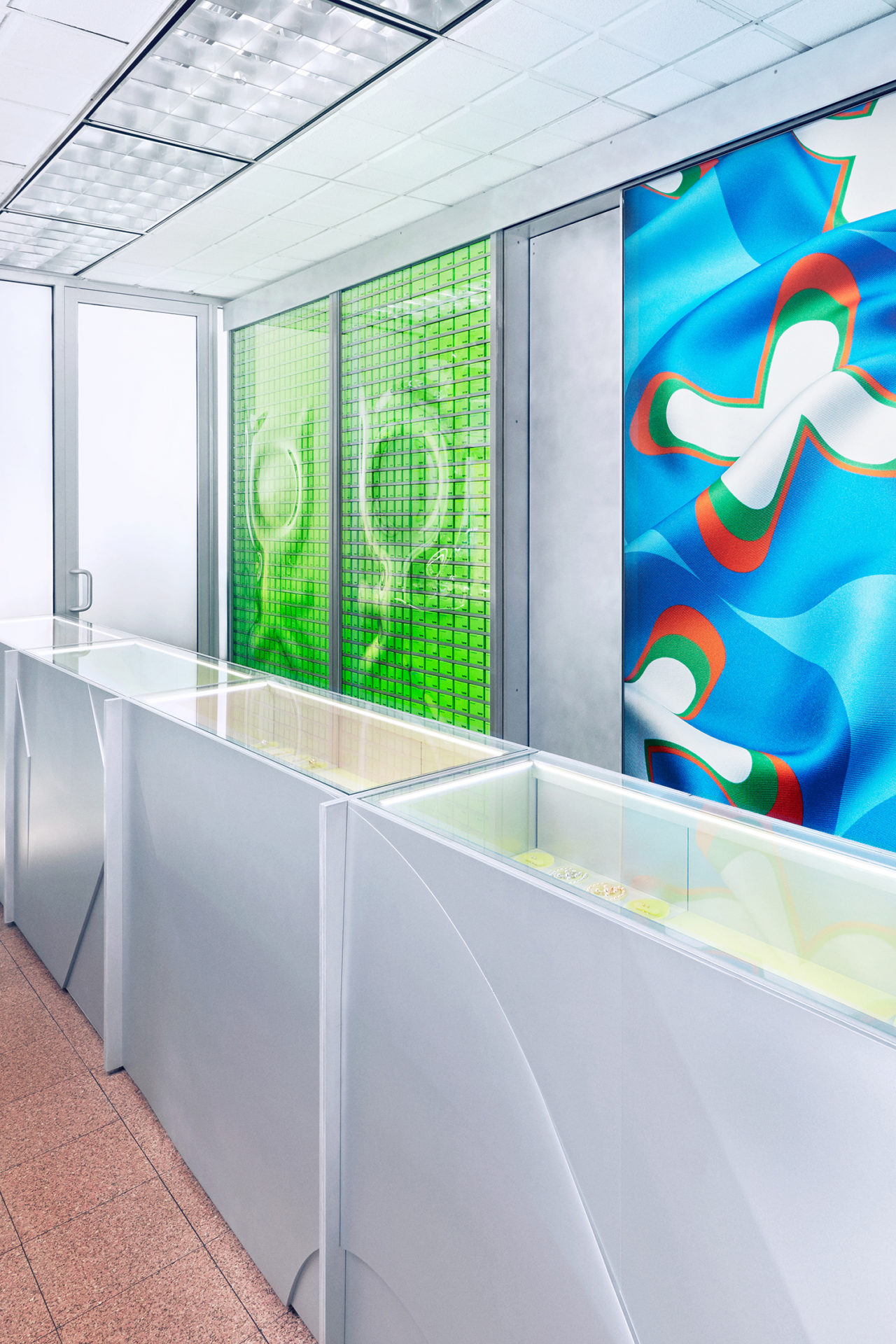 Rendering of a retail interior with graphic green and blue posters and steel casing with jewelry.