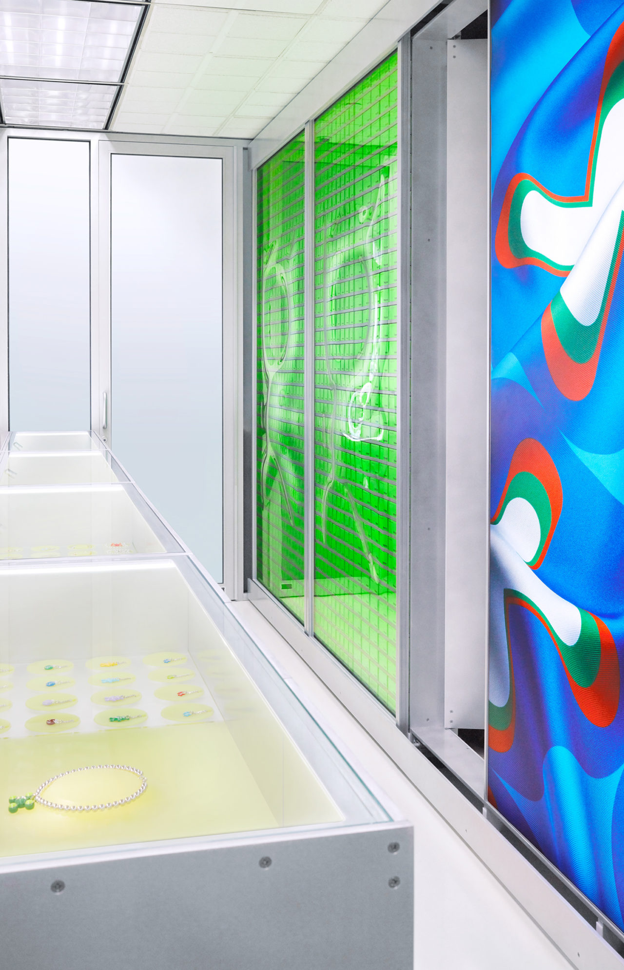 Rendering of a retail interior with graphic green and blue posters and steel casing with jewelry.