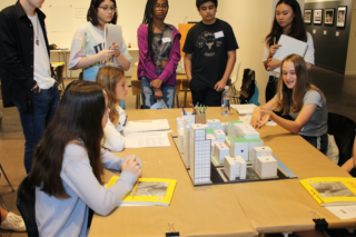 High School students gathered around a box model of a neighborhood