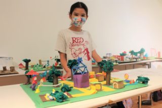 Student standing behind a scale model of a playground