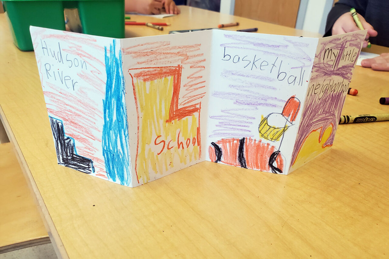 An accordion book with student illustrations on the front