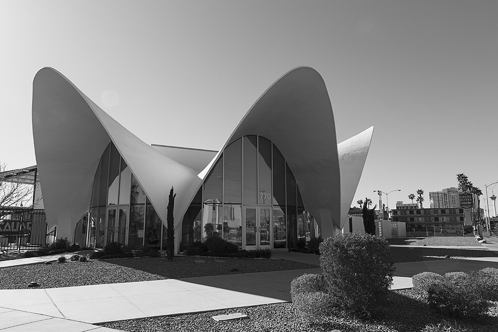 Black and white image of a one-story building with dramatic curved facade