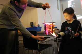 Parent and child illuminating a homemade lantern with a flashlight