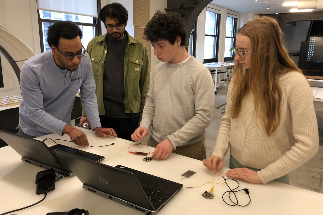 Two architects and two high school students look at computers