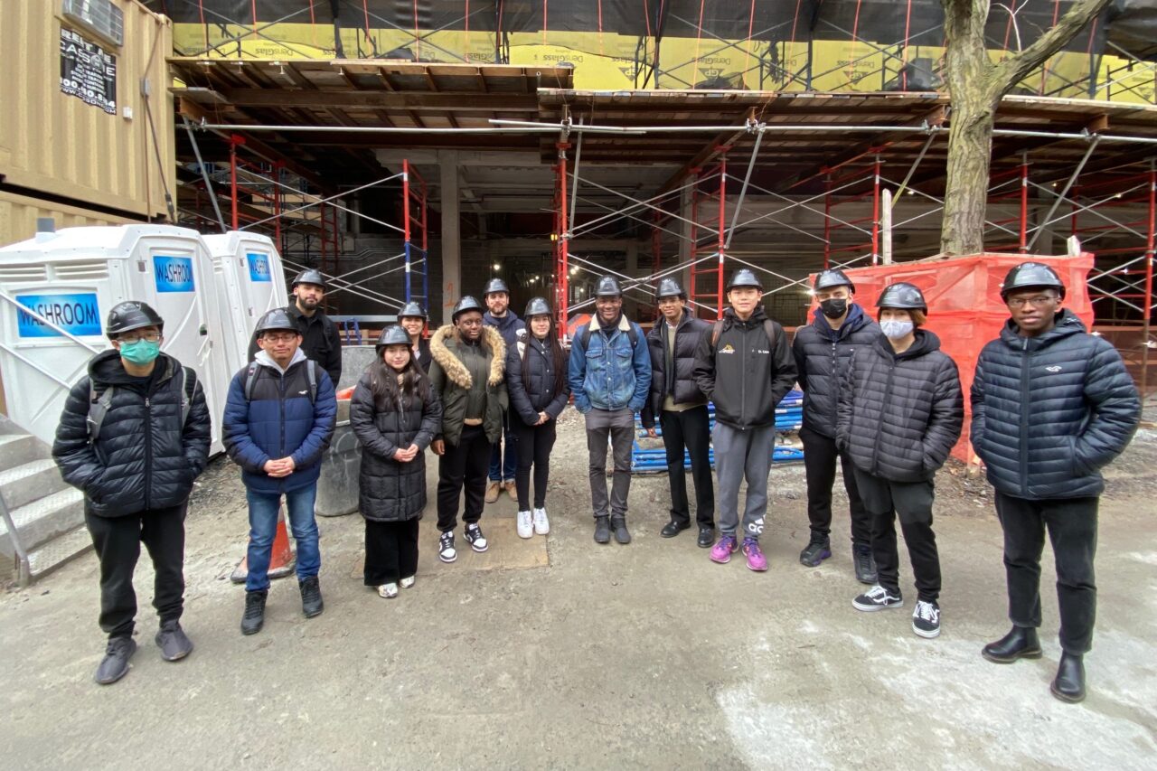 Group photo of high school students and architects on a site visit at a construction site
