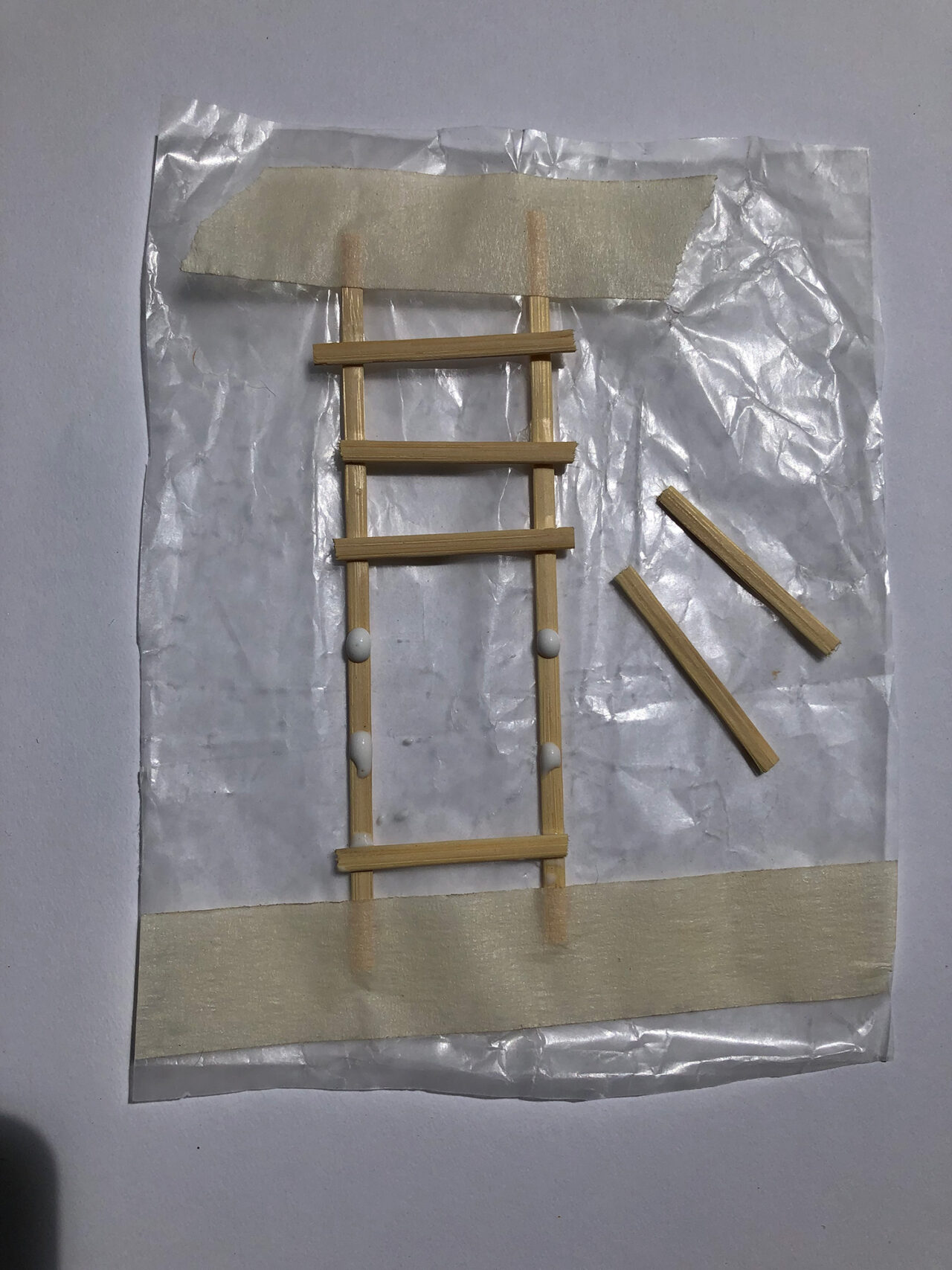 Wooden sticks and glue are arranged to create a ladder.