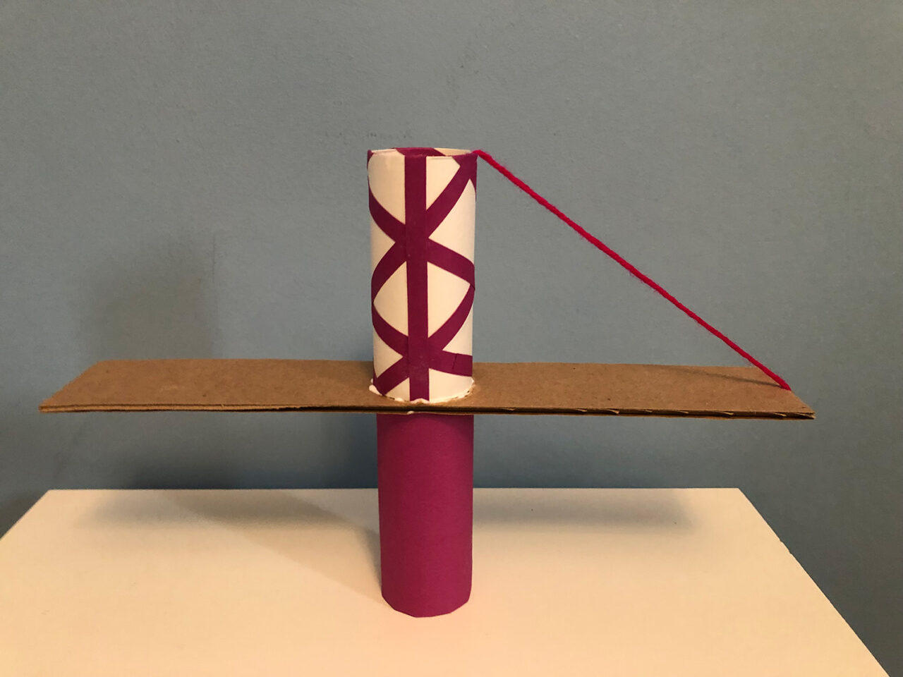 The beginning of the bridge assembly: one piece of string is glued on the tube and cardboard