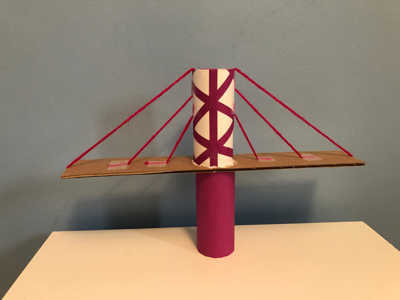 A model bridge made of paper tubes, string, and cardboard