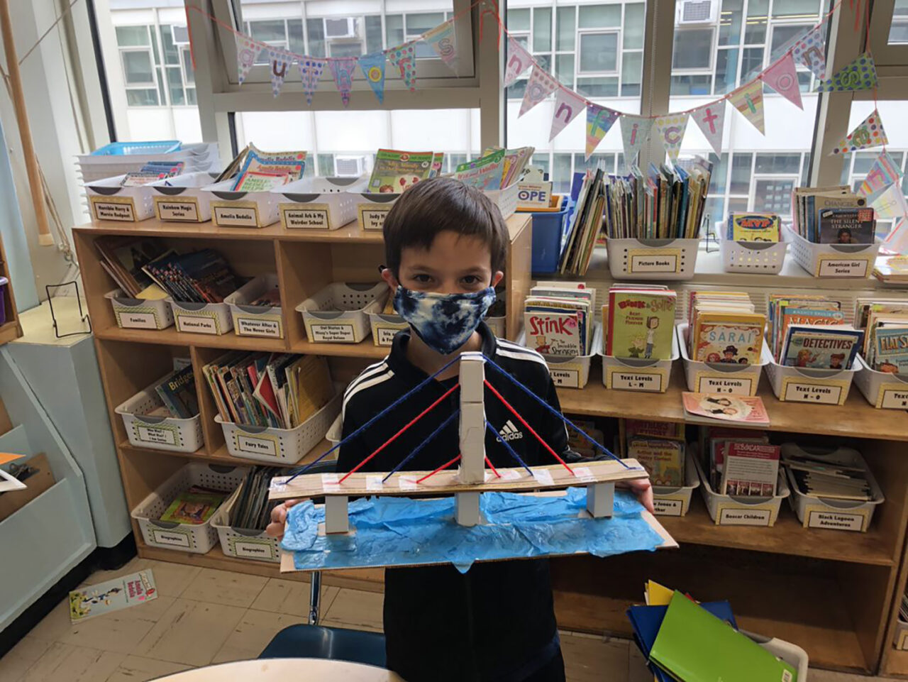 Boy holds up a bridge model