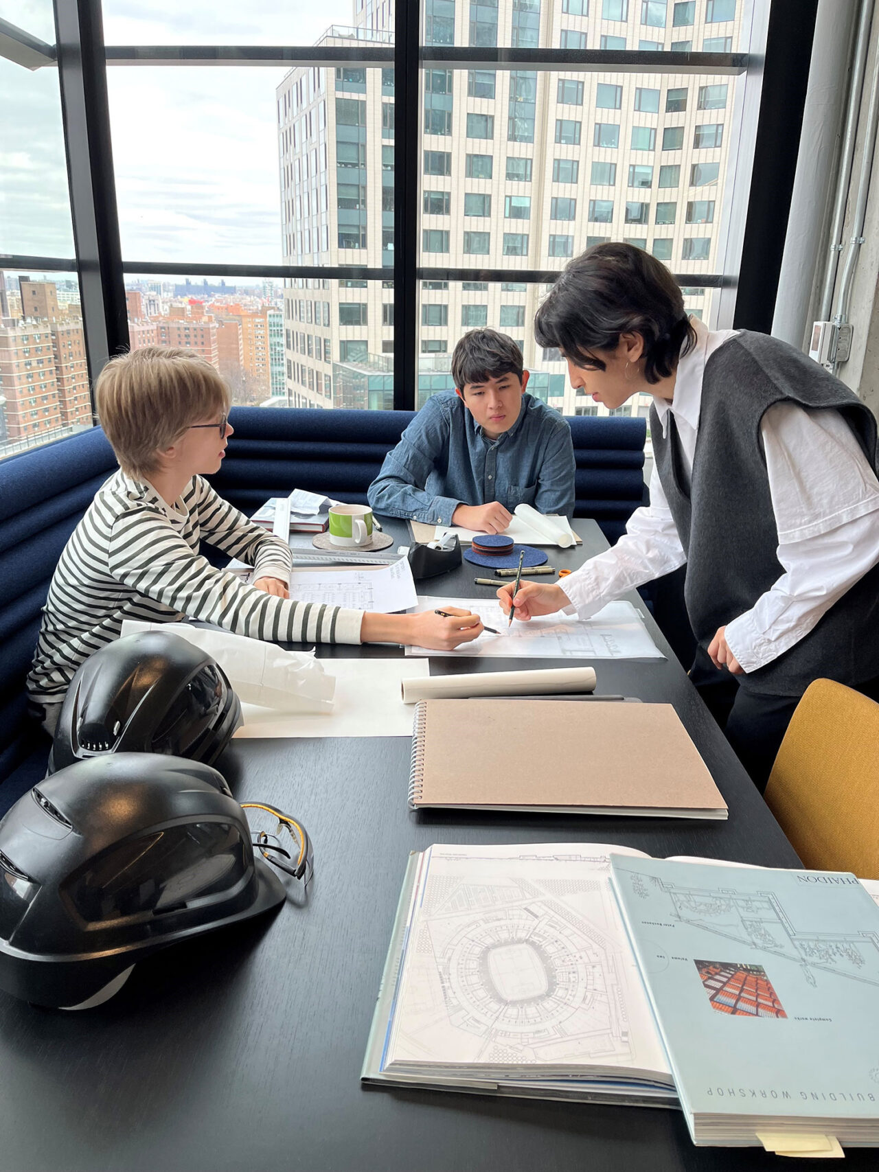Students gathered around a table talking about illustrations