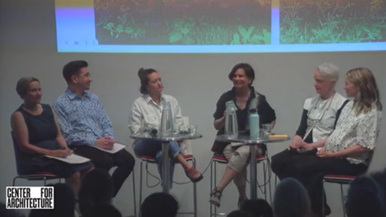 Six people sitting semicircular in front of an audience.