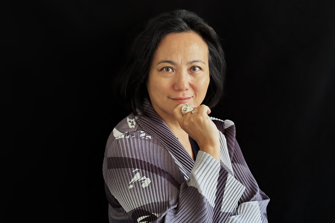 A portrait of a fair-skinned Asian woman with dark short hair against a black background.