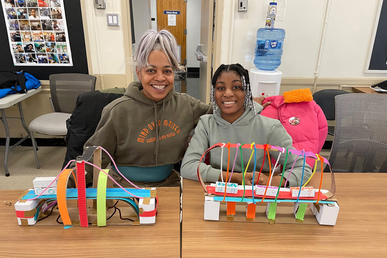 Mom and daughter smile with their bridge models.
