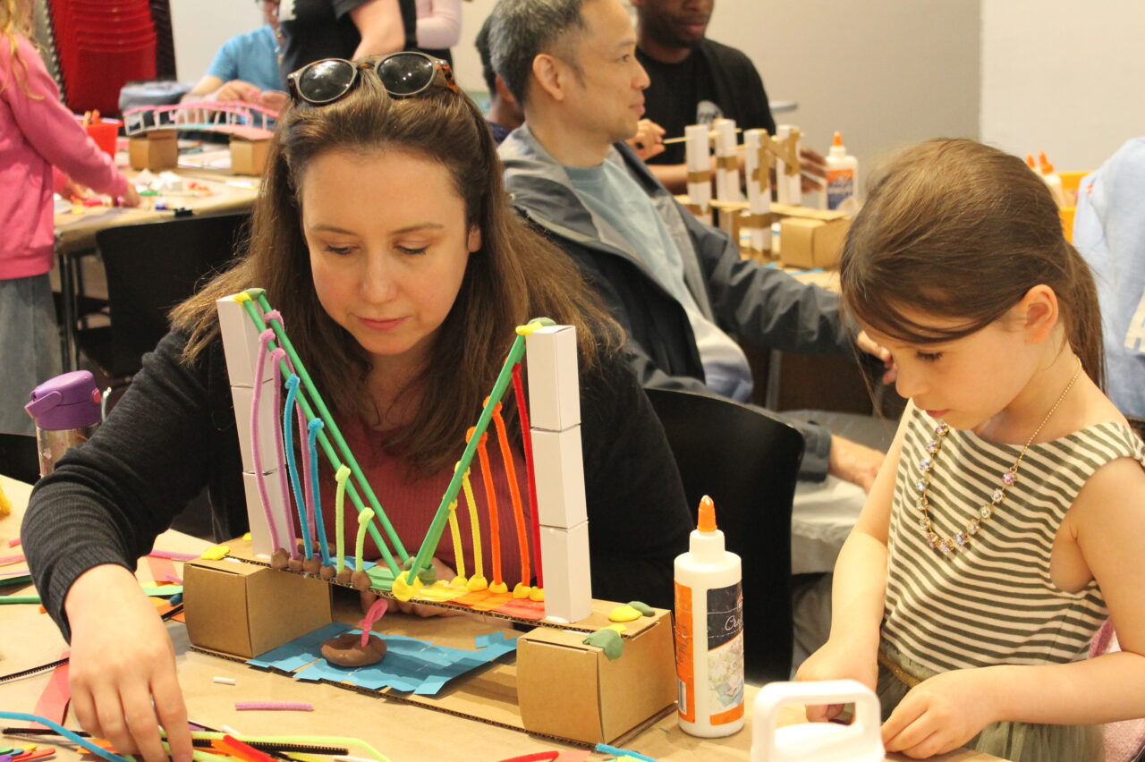 Mother and daughter building a rainbow suspension bridge.