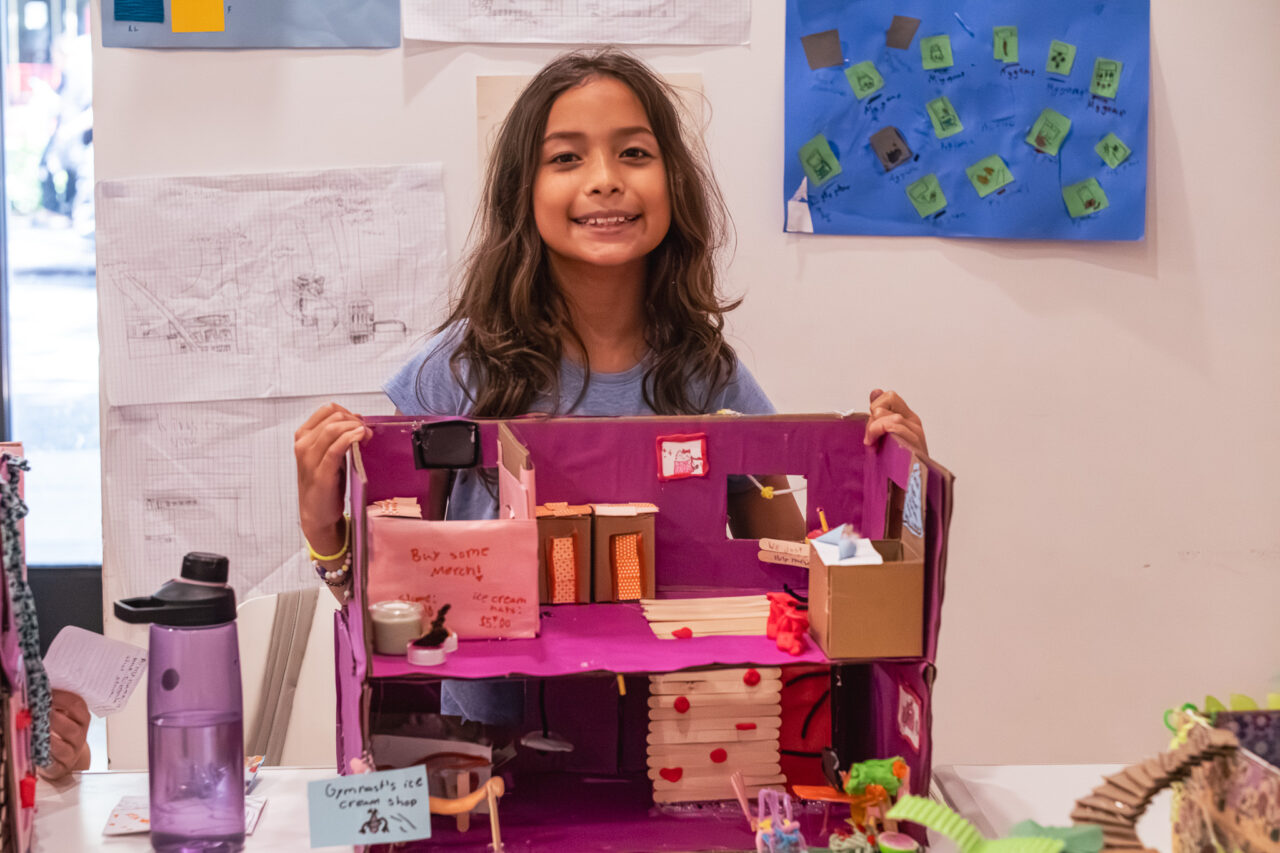 Elementary school student sitting behind a model store