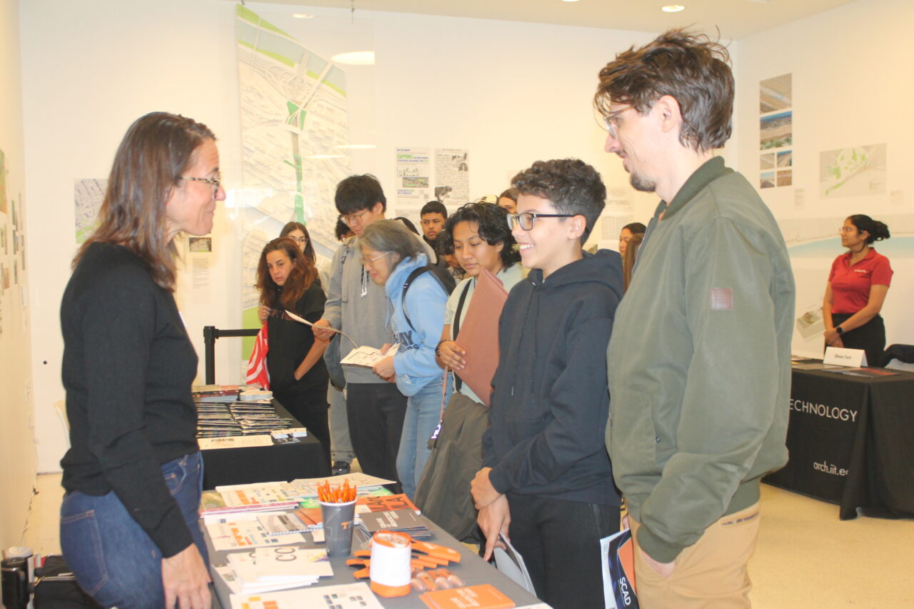 Group of high school students and parents speaking with college representative.