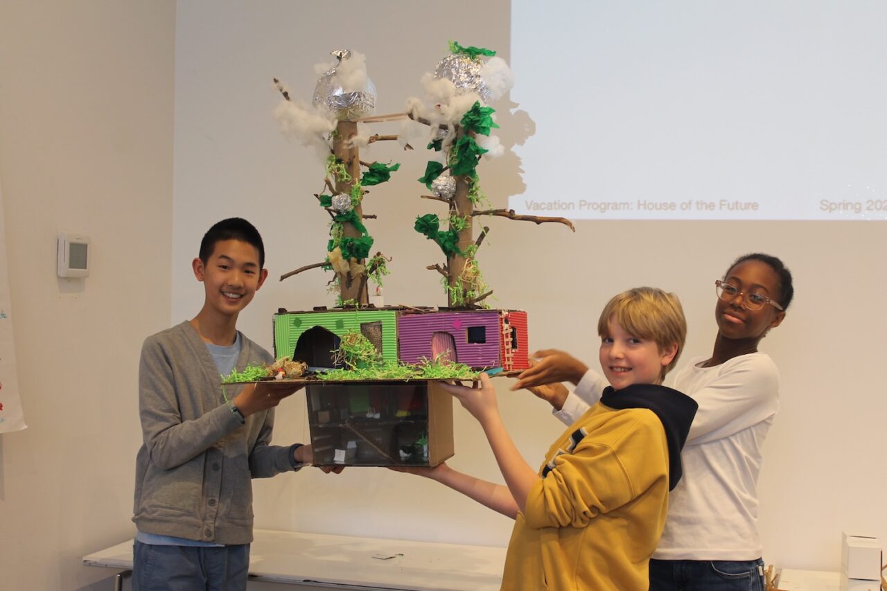 Three middle school students holding their large model of a house of the future.