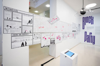 Corner of exhibition installation featuring iPad and Soundtube speaker in front of large mural