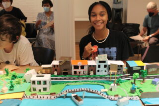 Middle school student posing with their potion of a waterfront city model