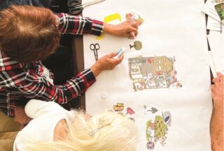 Top down view of two people drawing an architectural layout.