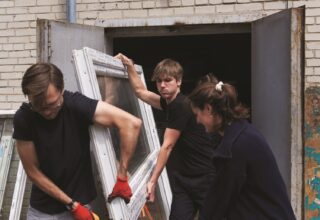 Three people moving a window.