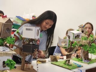 Middle school student showing model treehouse.